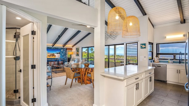 Una cocina moderna con armarios blancos, una isla grande y vistas al exterior.