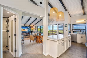 A modern kitchen with white cabinets, a large island, and a view of the outdoors.