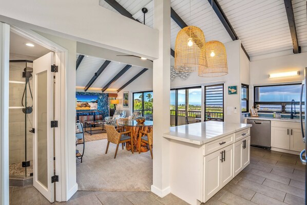 A modern kitchen with white cabinets, a large island, and a view of the outdoors.