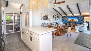 Una cocina amplia con una isla grande, un comedor con sillas de madera y un ventilador de techo.