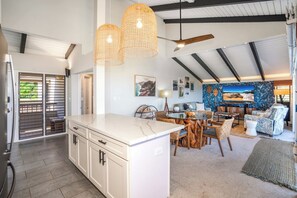 A spacious kitchen with a large island, a dining area with wooden chairs, and a ceiling fan.