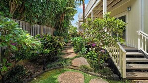 A garden pathway with steps leading to a building, surrounded by lush greenery and plants.