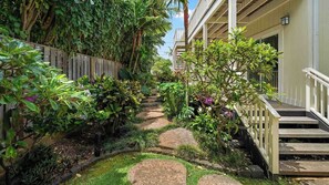 A garden pathway with steps leading to a building, surrounded by lush greenery and plants.