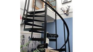 Un escalier en colimaçon agrémenté de panneaux indicateurs pointant vers New York, Londres et Hong Kong.
