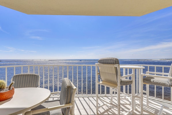 A balcony with white railings, a round table, and two chairs with striped cushions. - Stunning View in Waterview Towers Yacht Club 532 (Destin)