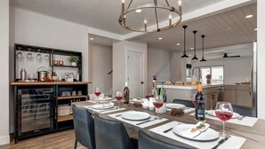 A modern kitchen with a dining area, featuring a built-in oven, wine glasses, and a chandelier. - Alpine Adventure Haus! 4BR Townhome 15m to Main (Heber City)