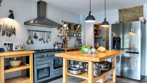 Una cocina moderna con una isla central, electrodomésticos de acero inoxidable y estantes de madera.