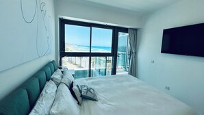 A bedroom with a large bed, a view of the beach, and a mounted TV. - "Stunning sea and beach view apartment Herzeliya Pituach beach" (Herzeliya Pituach)
