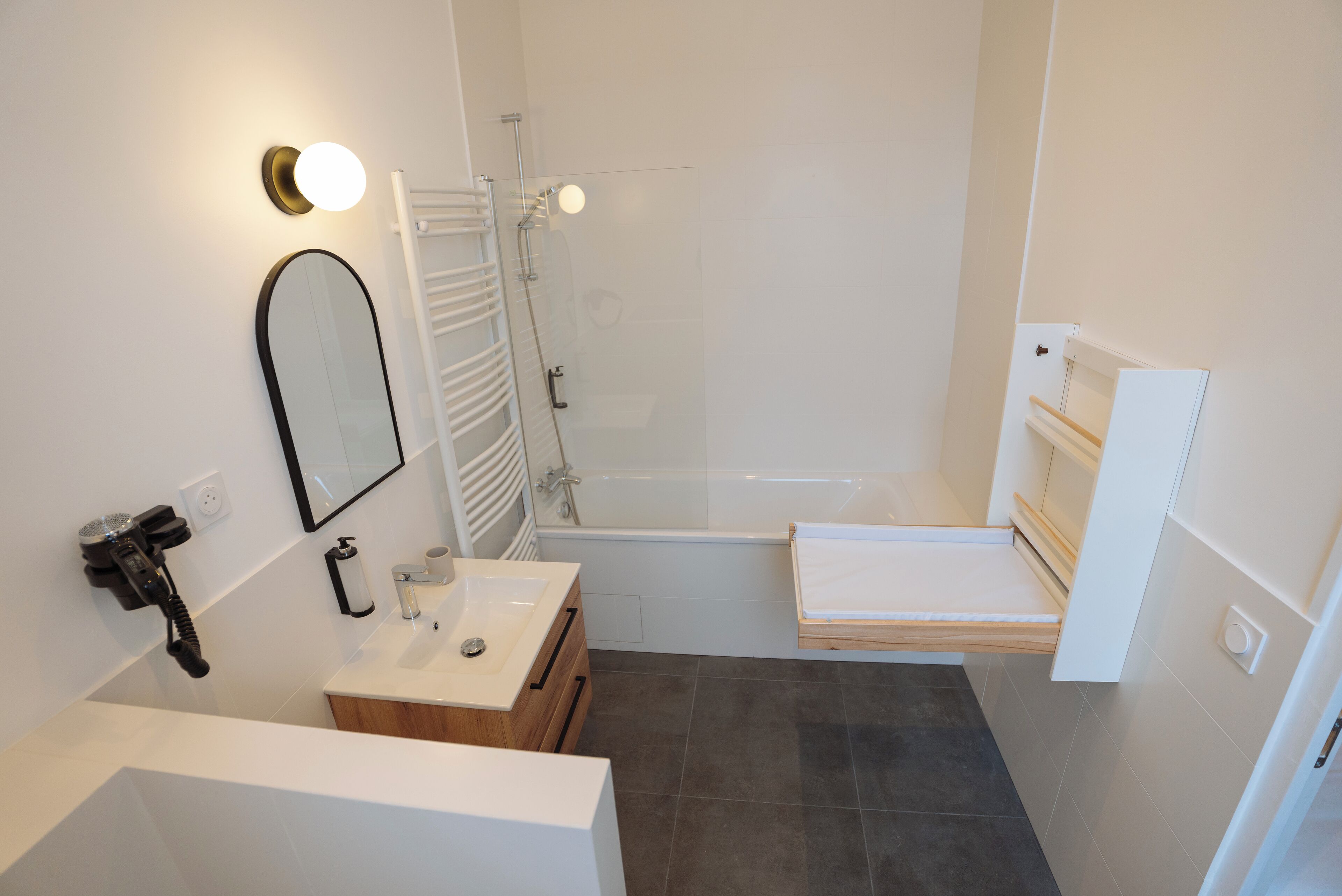 A modern bathroom with a shower, a sink, a mirror, and a towel rack.