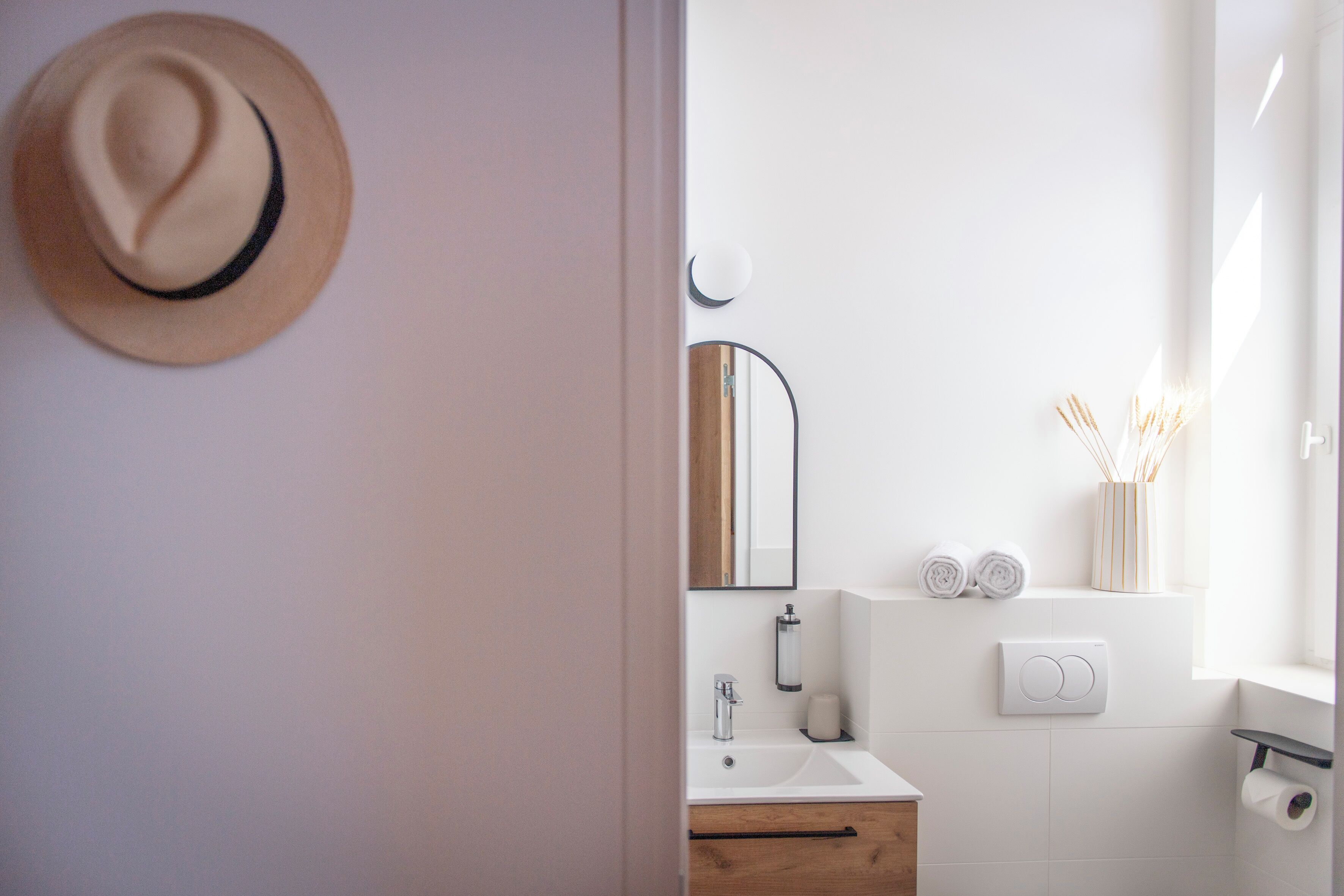 A modern bathroom with a white sink, wooden cabinet, and a mirror.