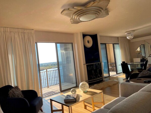 Een ruime woonkamer met balkon, een eethoek en een groot raam met uitzicht op de omgeving.