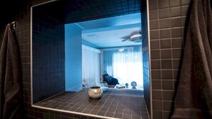 A bathroom with a large mirror, a sink, and a decorative vase.