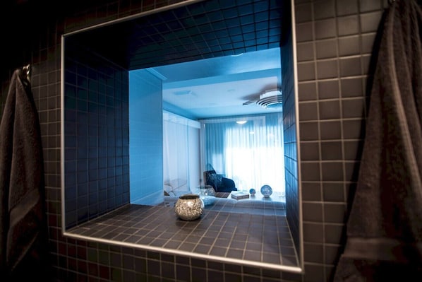 Een badkamer met een grote spiegel, een wastafel en een decoratieve vaas.