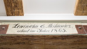 A wooden sign with the inscription "Lenin & Moskiewicz erbaut im Jahre 1865." - Miodowa Faktoria 7 (Torun)