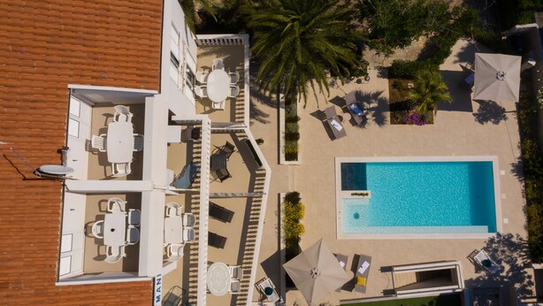 An aerial view of a resort with a swimming pool, sun loungers, and a covered patio area. - Seagull Apartments & Studios (Novalja)