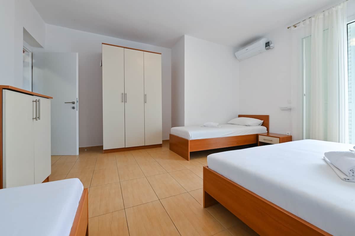 Hotellihuone, jossa on sänky, vaatekaappi, yöpöytä ja ikkuna, jossa on verhot.