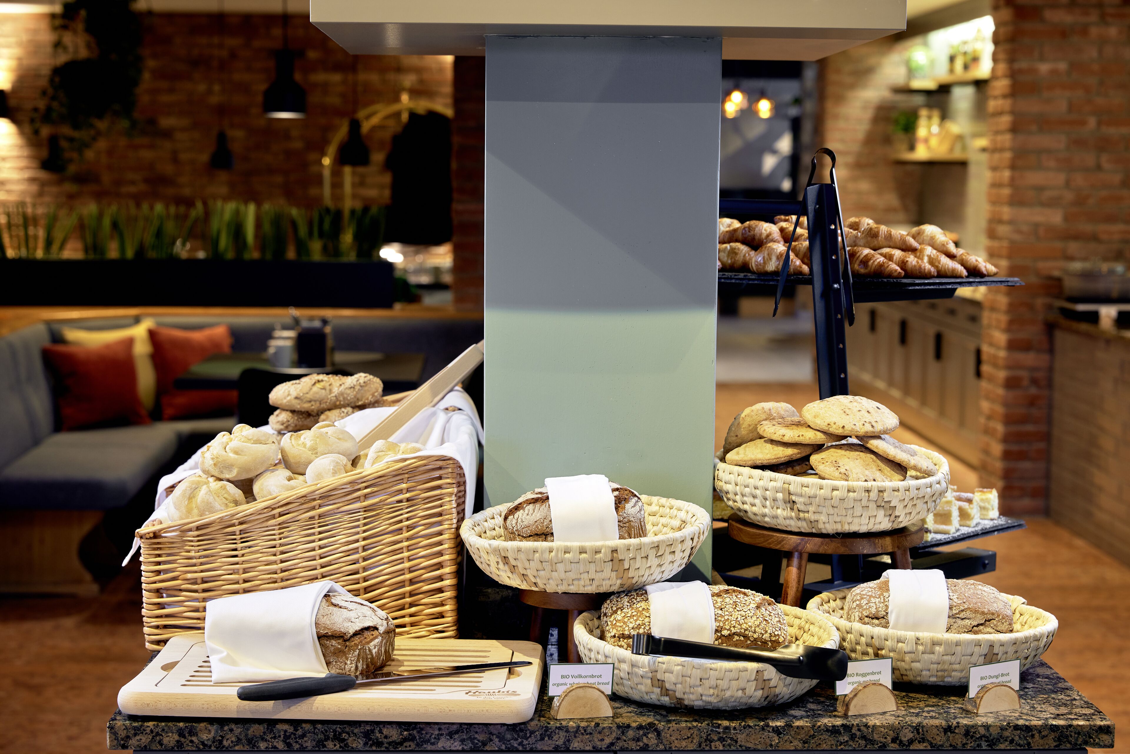 A buffet area with various breads and pastries displayed in baskets and on a counter.