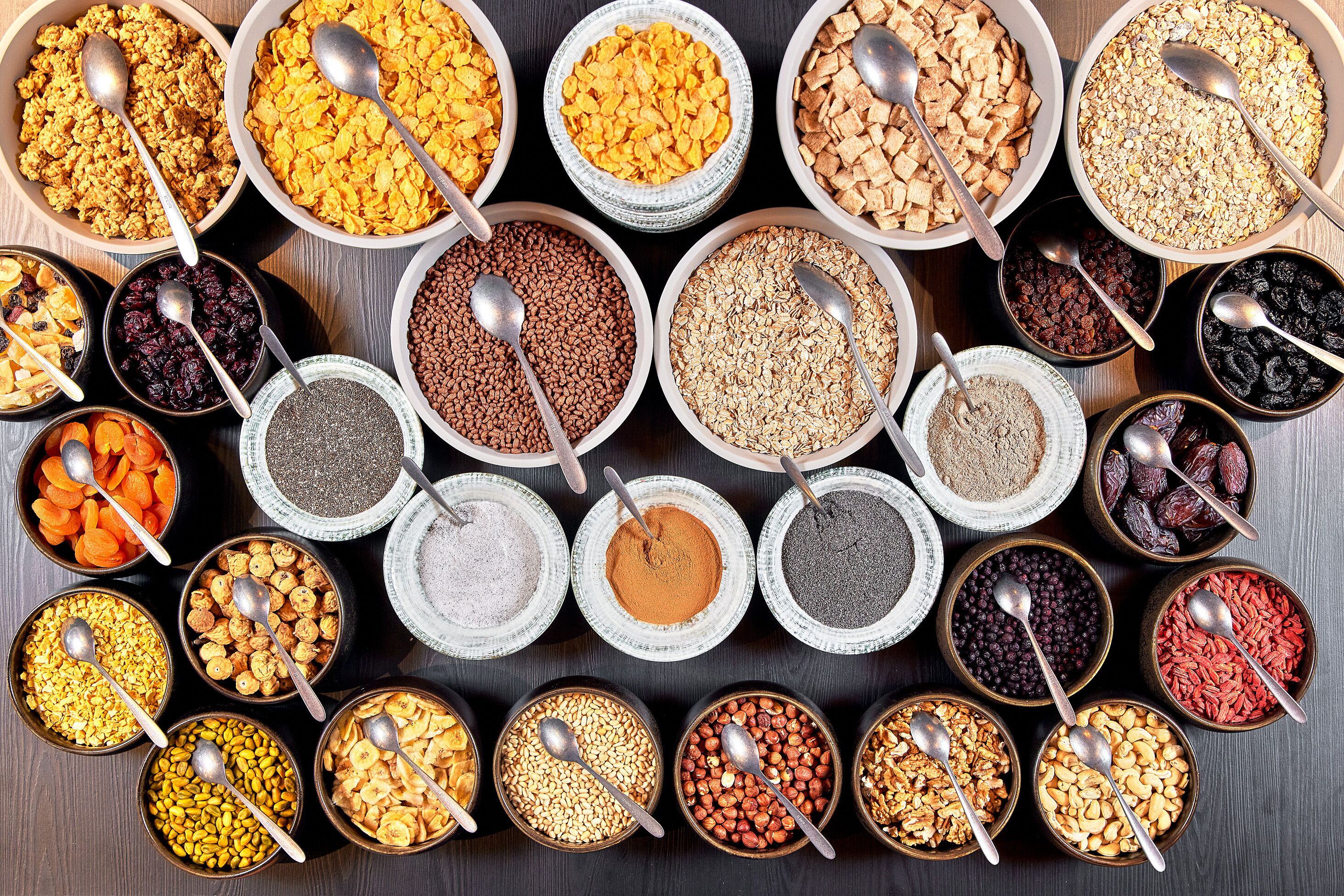 A variety of food items in bowls, including cereals, nuts, and dried fruits.
