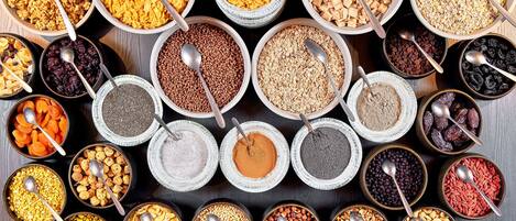 A variety of food items in bowls, including cereals, nuts, and dried fruits.