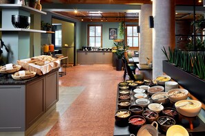 A buffet setup with various food items and a kitchen area in the background.