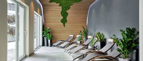 Un área de espera moderna con sillones y plantas en macetas.