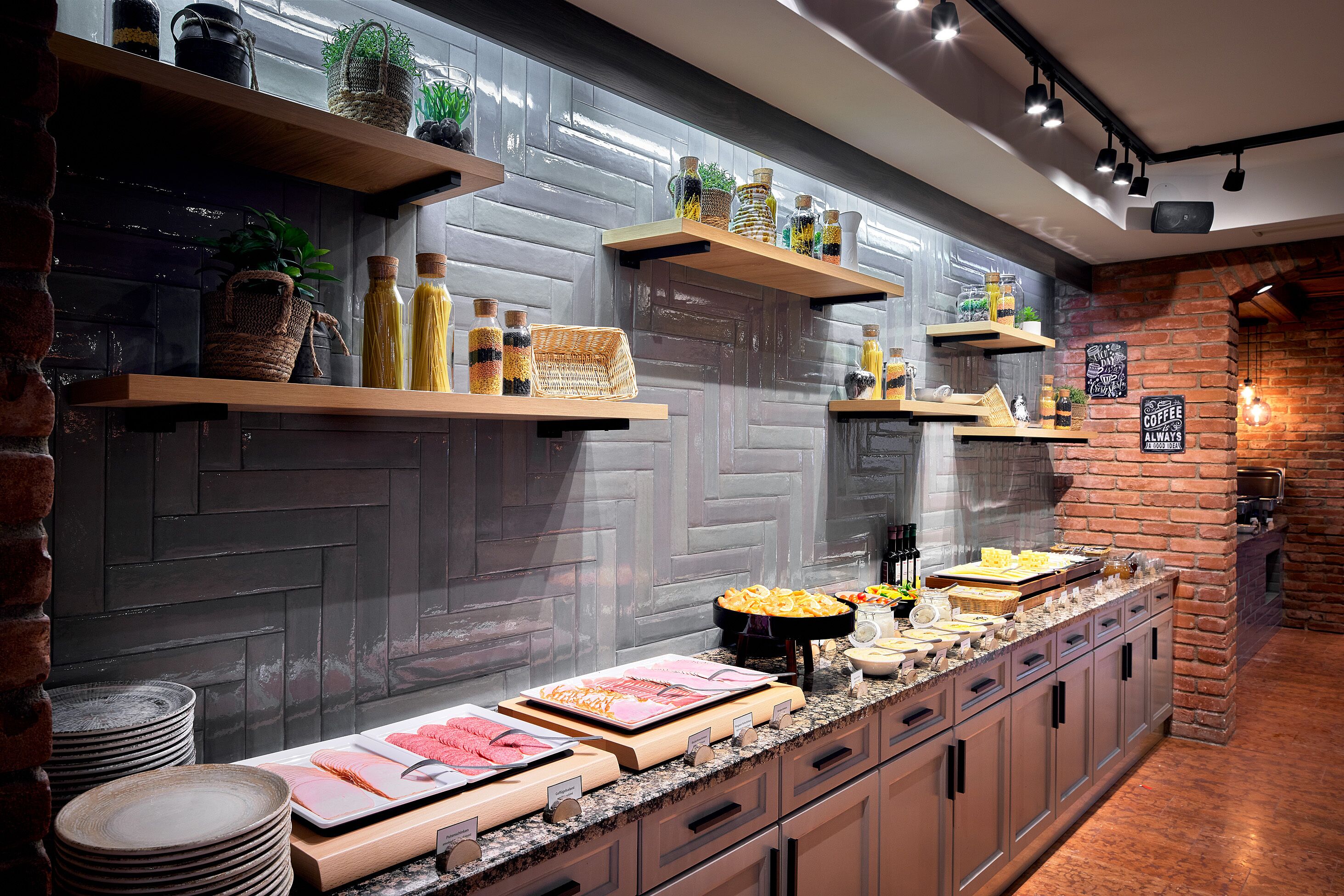 Een keuken met houten planken met keukengerei en planten, een buffet met diverse etenswaren, en een bakstenen muur.