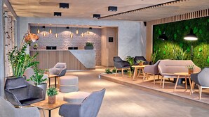 A modern reception area with a reception desk, seating area, and a green wall with plants. - ever.grün Kaprun (Kaprun)