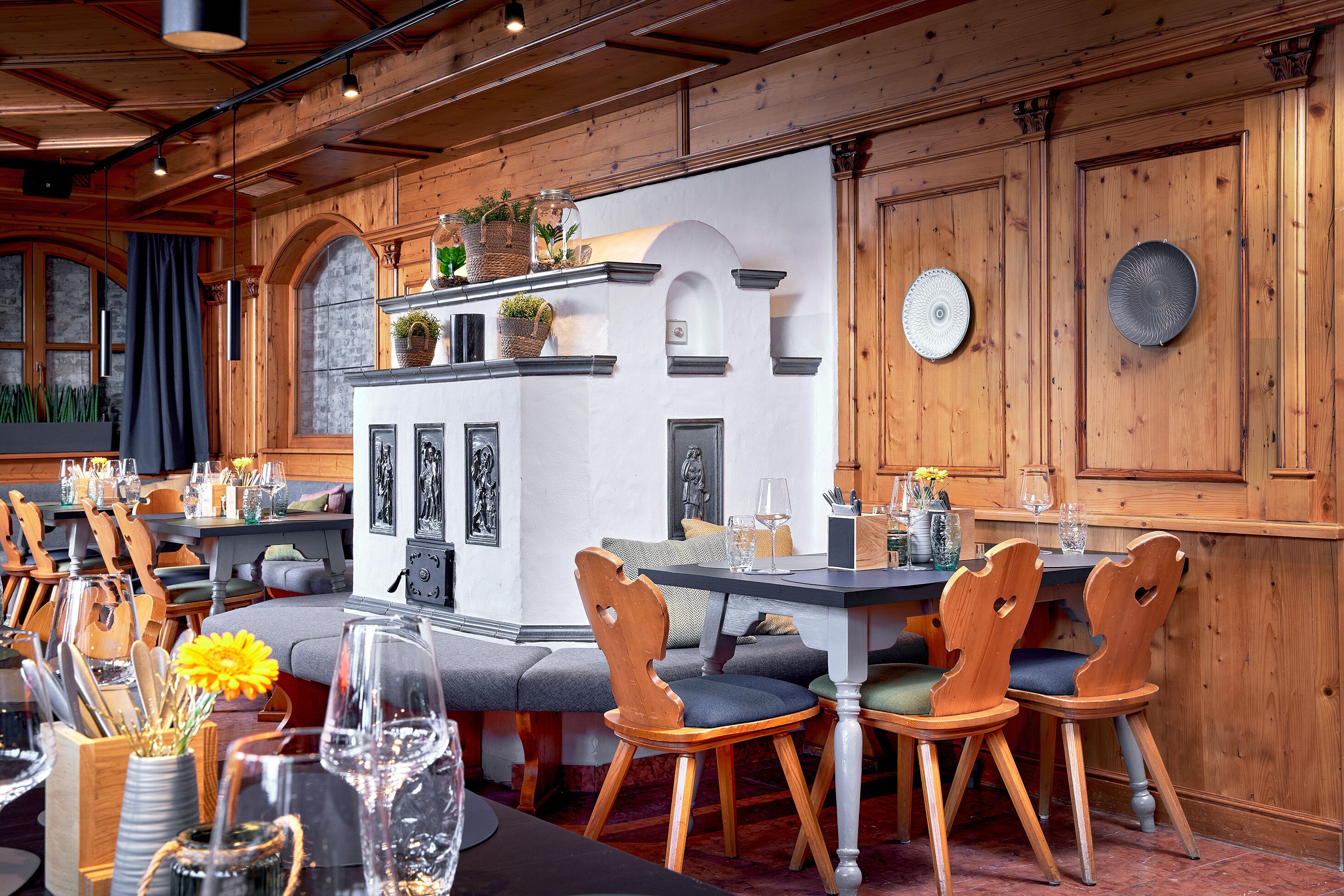 A dining area with wooden furniture, a central island with plants, and a stone wall.