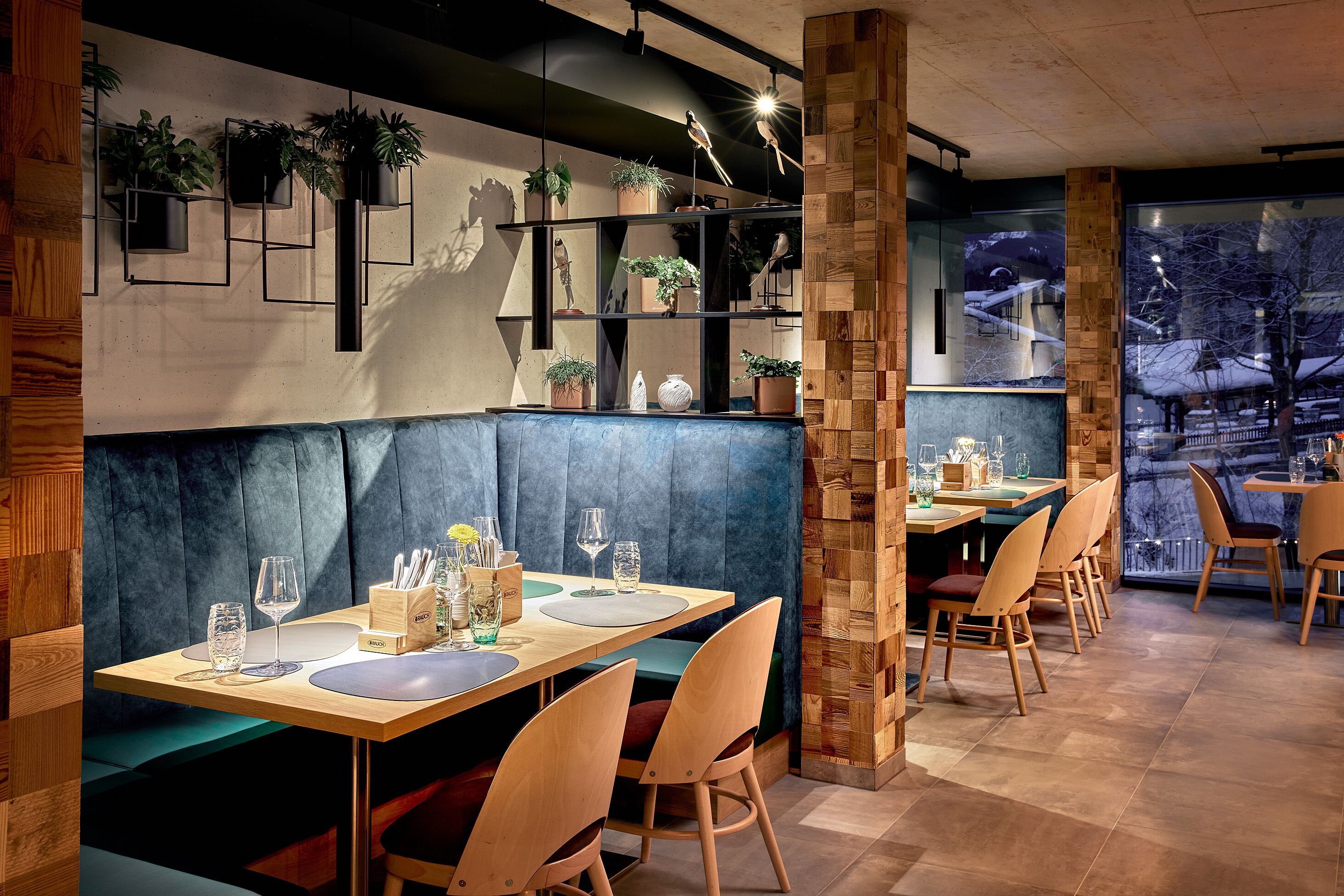 Un restaurant amb seients privats, taules de fusta i prestatgeries plenes de plantes.