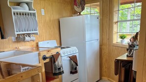 A compact kitchen with wooden walls, a white stove, a refrigerator, and a window with a view of trees. - Fox Pen Cabins
Cabin #2
Not friendly for street bikes…
Pet-Friendly (Eminence)
