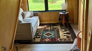 A cozy, triangular room with a bed, a rug, and a window offering a view of a green landscape. - Fox Pen Cabins
Cabin #2
Not friendly for street bikes…
Pet-Friendly (Eminence)