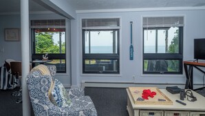 Ein modernes Wohnzimmer mit großen Fenstern, einem Sofa, einem Tisch mit Tablett und einem Fernseher.