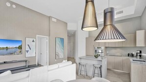 Een moderne woonkamer met een televisie, een bank en een eethoek met een tafel en stoelen.