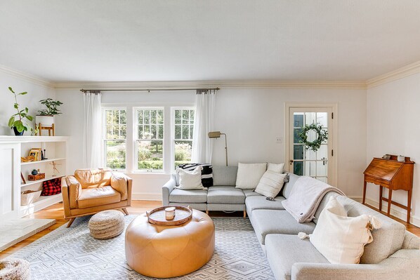A living room with a sofa, ottoman, and a bookshelf.