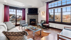 A modern living room with a fireplace, large windows, and a view of the outside.