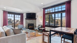 A modern living room with a fireplace, large windows, and a dining area.