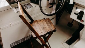 A compact, cabin-style interior with a wooden ceiling, a steering wheel, a control panel, and a small wooden chair. - Lost Hill Lake Sunshine Skoolie, The Sunshine Skoolie - Lost Hill Lake (Saint Clair)