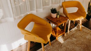 A room with two mustard-colored chairs, a small wooden table with a potted plant, and a patterned rug. - Lost Hill Lake Sunshine Skoolie, The Sunshine Skoolie - Lost Hill Lake (Saint Clair)