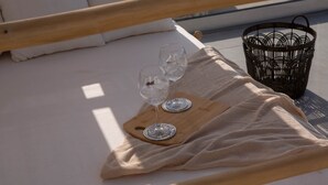 A bed with a wooden headboard, two wine glasses on a wooden tray, and a woven basket on the floor. - Armante Supreme Villas-Villa Nicole (Fterno)