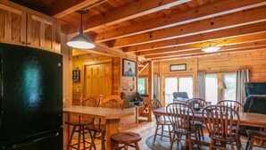 A wooden cabin interior with a dining area, kitchen, and living space. - Eagle Bend Lodge-center of Pine Creek Rail Trail (Brown Township)