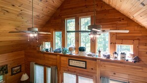 A cabin interior with wooden walls, a sloped ceiling, and a window overlooking a forest. - Eagle Bend Lodge-center of Pine Creek Rail Trail (Brown Township)