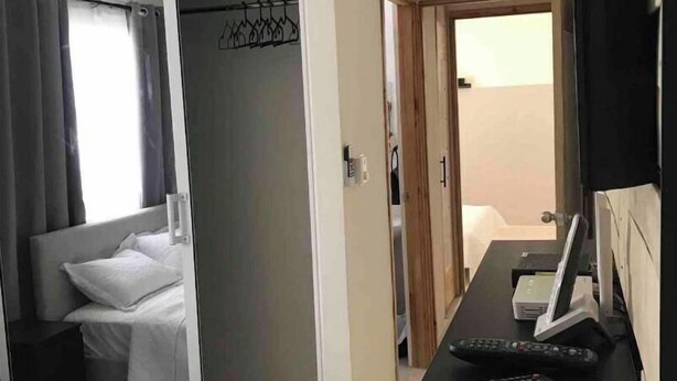 A bedroom with a bed, a desk with a computer and remote controls, a wardrobe, and a door leading to another room. - MODERN APARTMENT IN FRONT OF THE SEA. (E17AM502) (Santo Domingo)