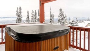A hot tub on a wooden deck with a view of snow-covered trees and mountains. - Big White Beauty! Sleeps 10.  Ski in/Ski out Chalet with Private Hot Tub. (Beaverdell)