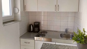 A kitchen with white cabinets, a stove, a sink, and a window. - Studio for 2 people in a quiet part of town (Baška)