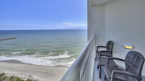 Een balkon met uitzicht op de oceaan, met twee stoelen en een klein tafeltje.