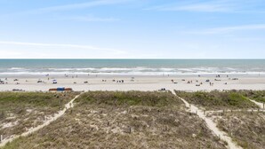 A beach with a sandy shore, a clear sky, and a few people and umbrellas. - Crescent Sands of Windy Hill  F4-3BR/3BA Oceanfront condo in Crescent Beach (North Myrtle Beach)