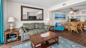 A living room with a sofa, coffee table, and a dining area with chairs and a table. - Crescent Sands of Windy Hill  F4-3BR/3BA Oceanfront condo in Crescent Beach (North Myrtle Beach)