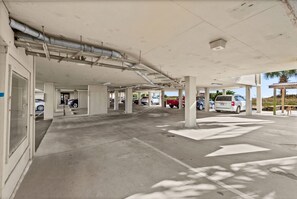 A parking garage with concrete pillars, directional arrows on the floor, and vehicles parked. - Crescent Sands of Windy Hill  F4-3BR/3BA Oceanfront condo in Crescent Beach (North Myrtle Beach)
