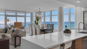 Una cocina moderna con una isla grande, armarios blancos y vista al océano.