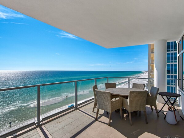 A balcony with a view of the beach and ocean.